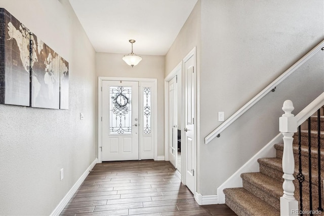 foyer with stairs, baseboards, and wood finished floors