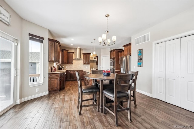 dining space with a notable chandelier, wood finished floors, visible vents, and baseboards