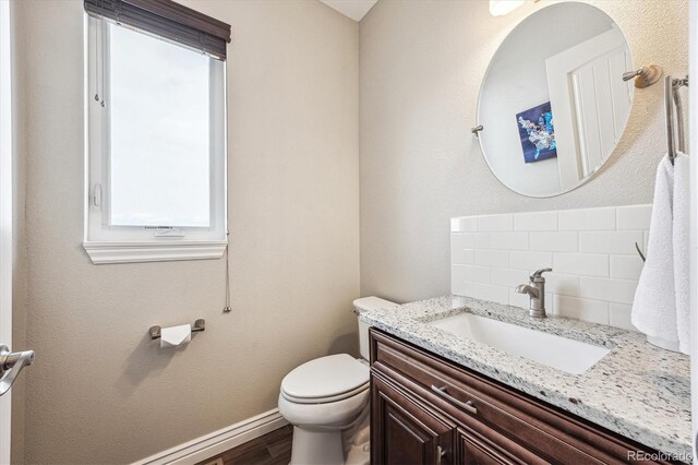 bathroom featuring tasteful backsplash, baseboards, toilet, wood finished floors, and vanity