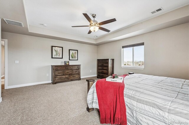 carpeted bedroom featuring baseboards, visible vents, and a tray ceiling