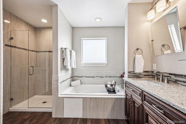 full bathroom featuring a garden tub, a shower stall, vanity, and wood finished floors