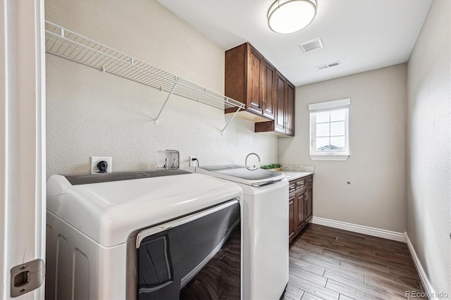 laundry area with visible vents, cabinet space, separate washer and dryer, and wood finished floors