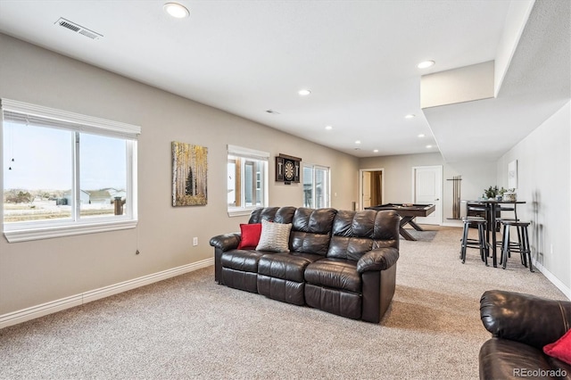 living area featuring a wealth of natural light, light colored carpet, visible vents, and baseboards