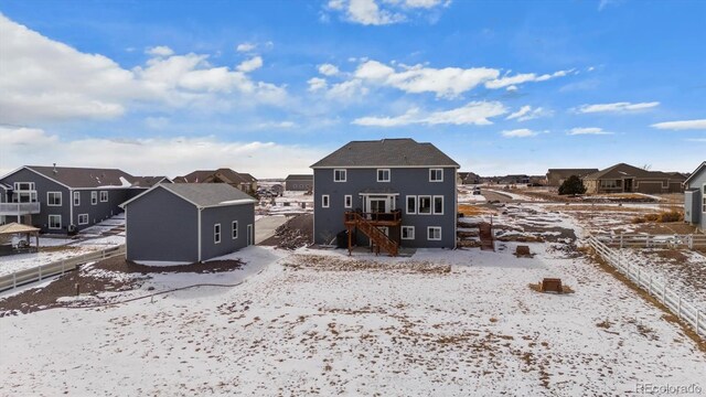 snow covered rear of property featuring a residential view, stairway, and a storage unit