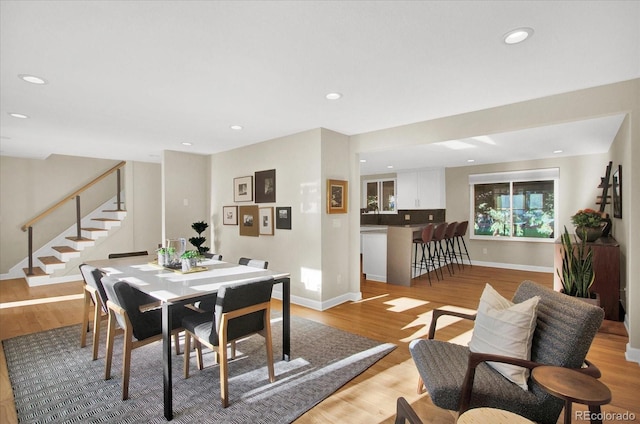 dining space with light wood-type flooring, baseboards, stairway, and recessed lighting