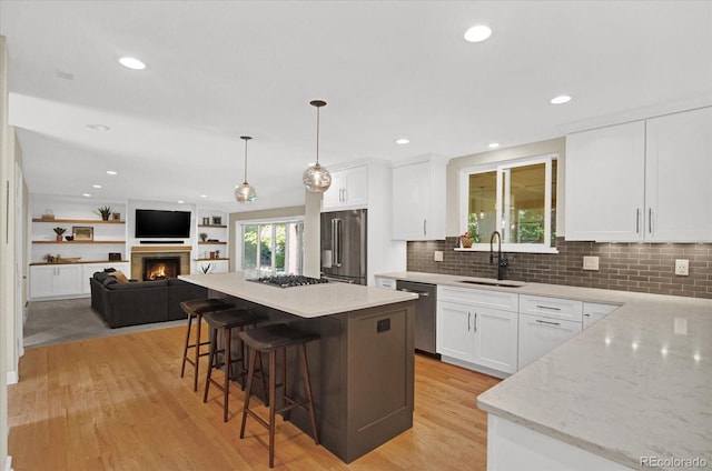 kitchen featuring stainless steel appliances, light wood finished floors, a breakfast bar area, and a sink