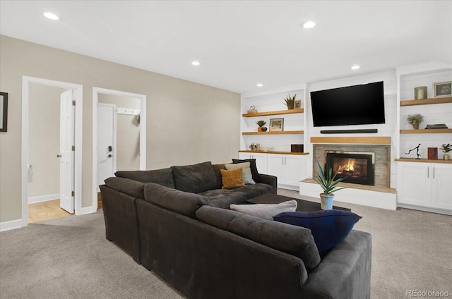 living area with baseboards, light colored carpet, a lit fireplace, built in shelves, and recessed lighting