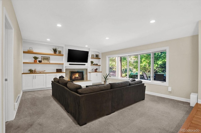 living area featuring a glass covered fireplace, baseboards, and recessed lighting