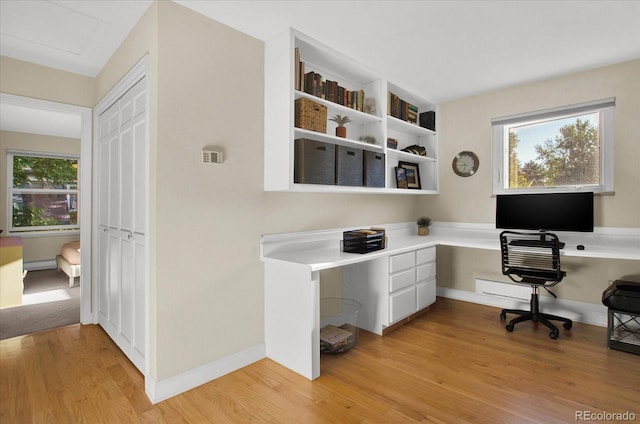 office featuring light wood-type flooring, plenty of natural light, baseboards, and built in desk