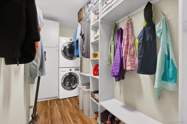 laundry area featuring laundry area, wood finished floors, and stacked washer and clothes dryer