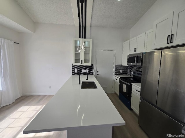 kitchen with glass insert cabinets, dark wood-type flooring, light countertops, decorative backsplash, and stainless steel appliances