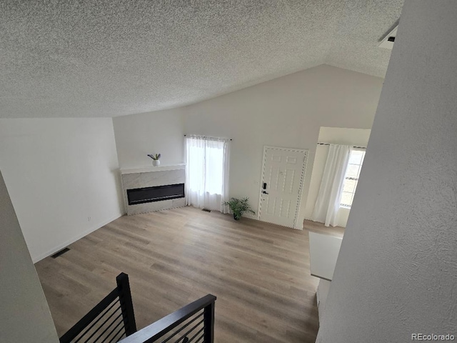 unfurnished living room with lofted ceiling, plenty of natural light, wood finished floors, and a fireplace