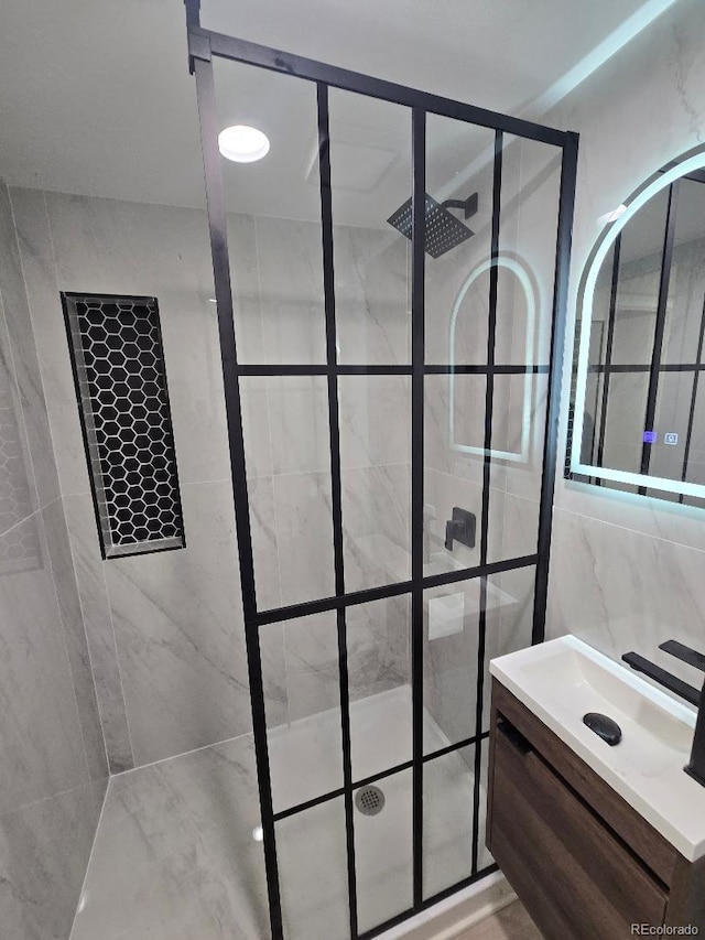 full bathroom featuring tile walls, vanity, and a tile shower