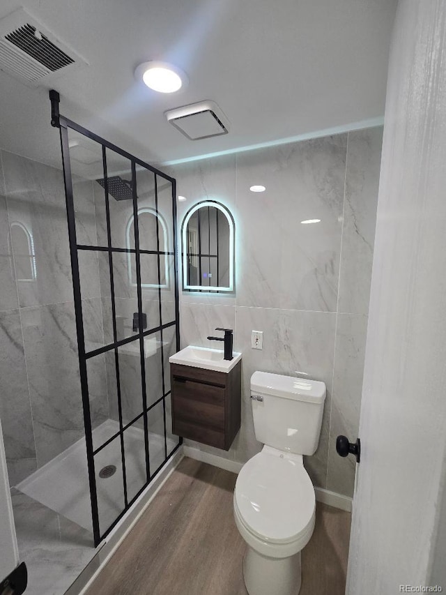 full bath featuring vanity, wood finished floors, visible vents, walk in shower, and toilet