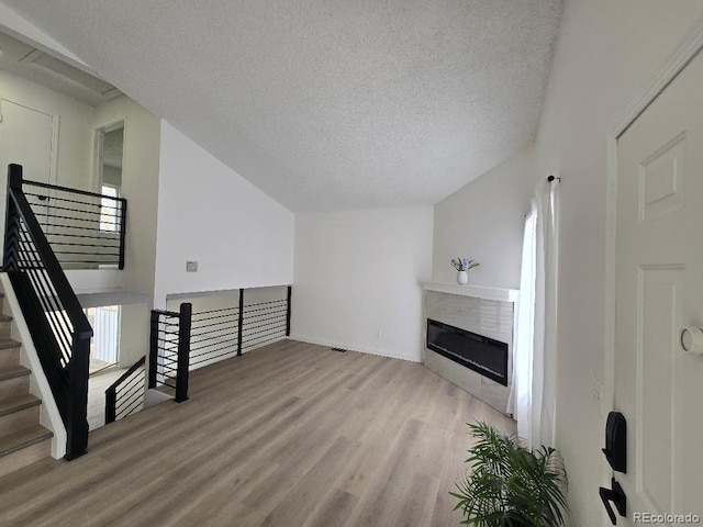 unfurnished living room with a glass covered fireplace, wood finished floors, and a textured ceiling
