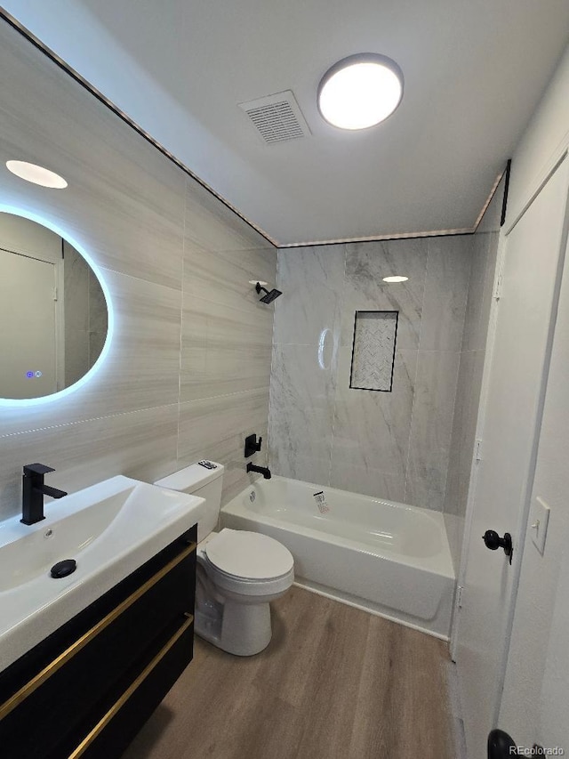 bathroom featuring wood finished floors, visible vents, toilet, vanity, and shower / tub combination