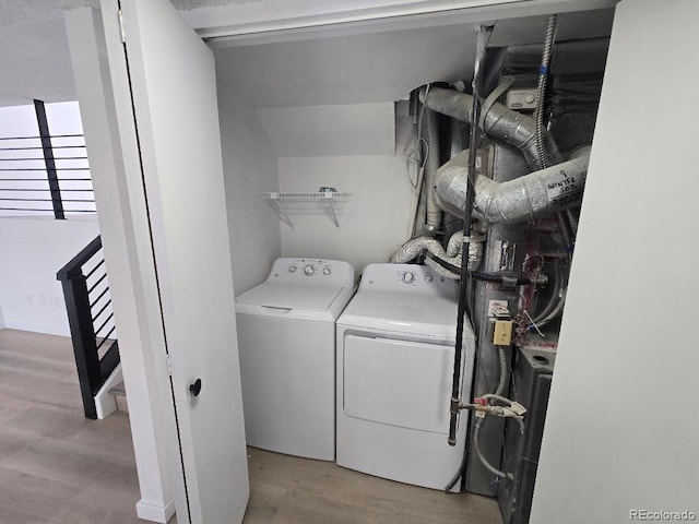 clothes washing area with independent washer and dryer, wood finished floors, and laundry area