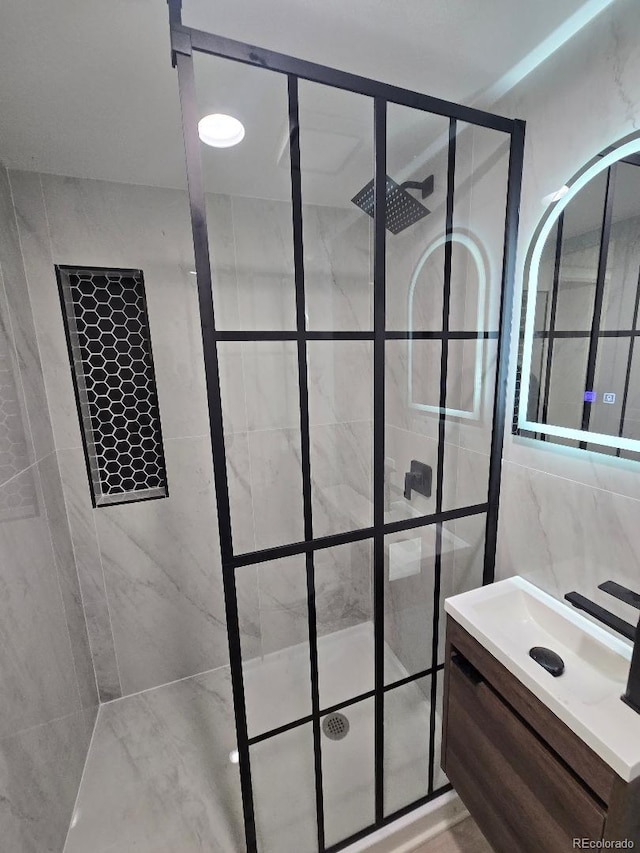 full bathroom featuring tile walls, vanity, and tiled shower