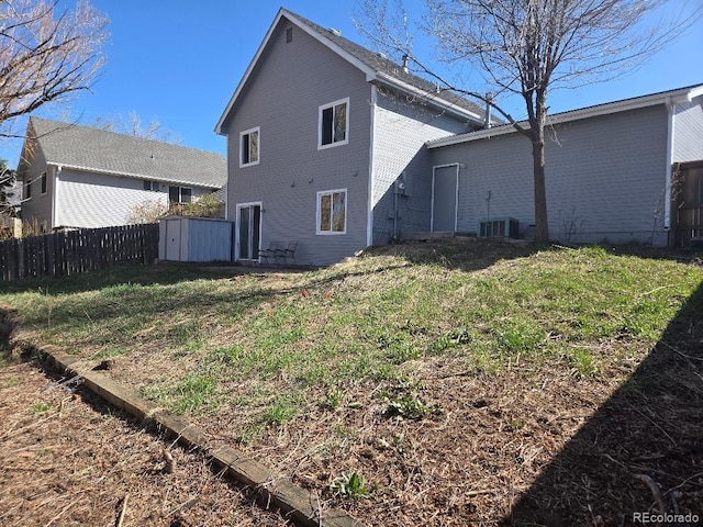 rear view of property featuring a storage shed, a lawn, fence, and an outdoor structure