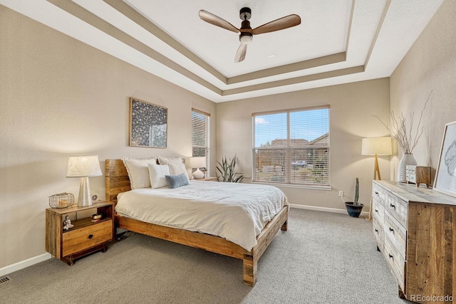 carpeted bedroom featuring a tray ceiling and ceiling fan