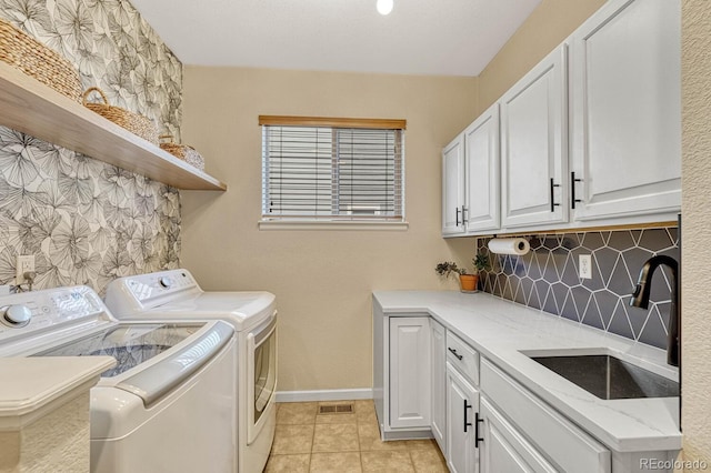 washroom featuring separate washer and dryer, sink, light tile patterned floors, and cabinets