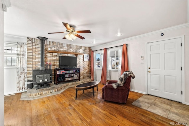 living room featuring a wood stove, hardwood / wood-style floors, a healthy amount of sunlight, and ornamental molding