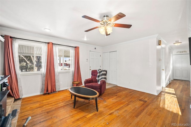 living area featuring hardwood / wood-style flooring, ceiling fan, and ornamental molding