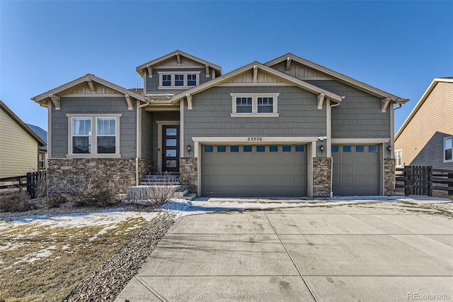 craftsman house with a garage, stone siding, fence, and driveway