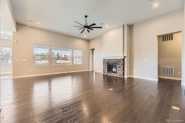 unfurnished living room featuring dark wood-type flooring, visible vents, and a stone fireplace