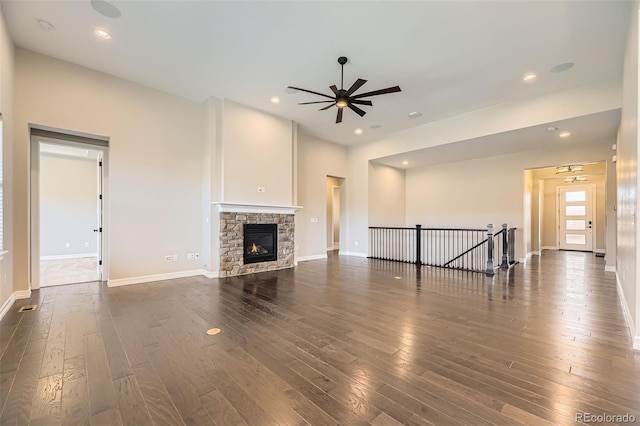 unfurnished living room with dark wood-style floors, recessed lighting, ceiling fan, and a stone fireplace