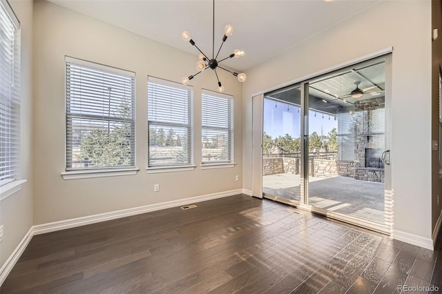 spare room featuring baseboards, dark wood finished floors, and ceiling fan with notable chandelier