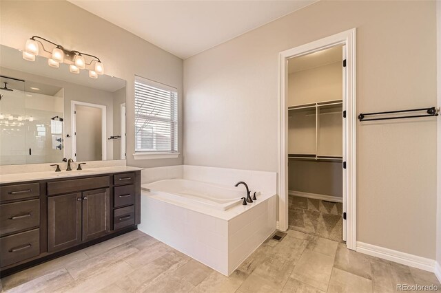 bathroom featuring a stall shower, baseboards, a walk in closet, vanity, and a bath