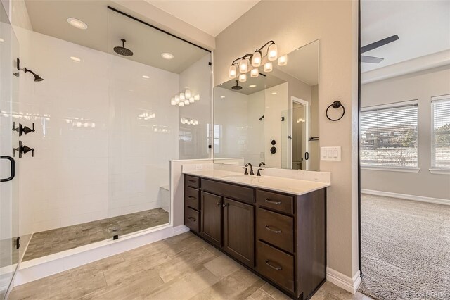 bathroom featuring a tile shower, vanity, and baseboards