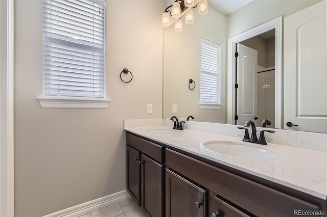 full bathroom featuring double vanity, tile patterned flooring, a sink, and baseboards