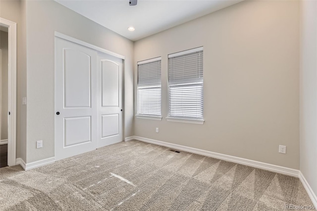 unfurnished bedroom with carpet floors, visible vents, baseboards, and a closet