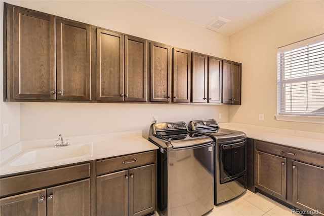 washroom featuring light tile patterned floors, separate washer and dryer, a sink, and cabinet space