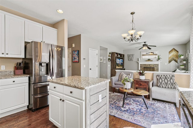 kitchen featuring dark wood-type flooring, open floor plan, ceiling fan with notable chandelier, and stainless steel fridge