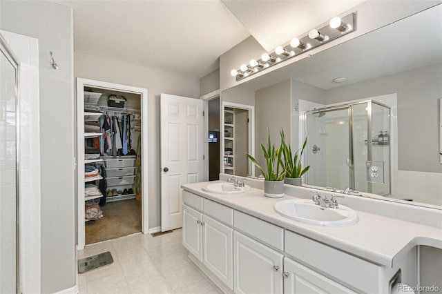 bathroom with a shower stall, a spacious closet, and a sink