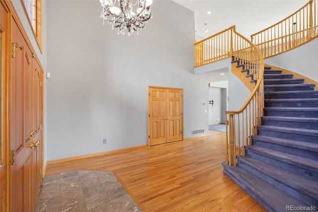 1680 Elk View Rd, Larkspur, CO 80118 - entrance foyer featuring wood finished floors, stairway, a high ceiling, a chandelier, and recessed lighting