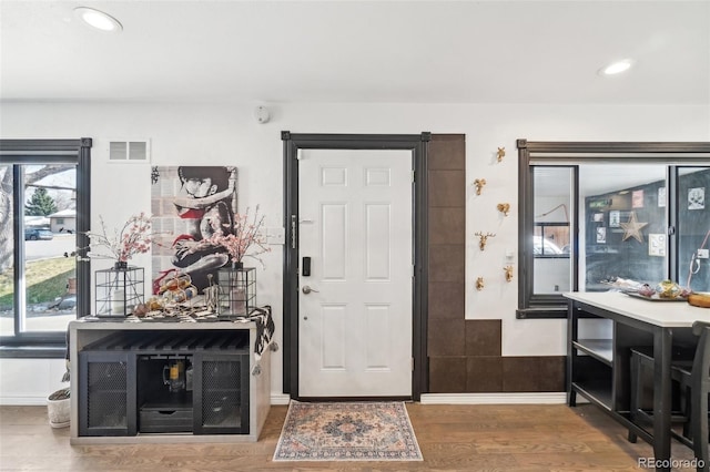 foyer entrance with wood finished floors, baseboards, visible vents, and recessed lighting