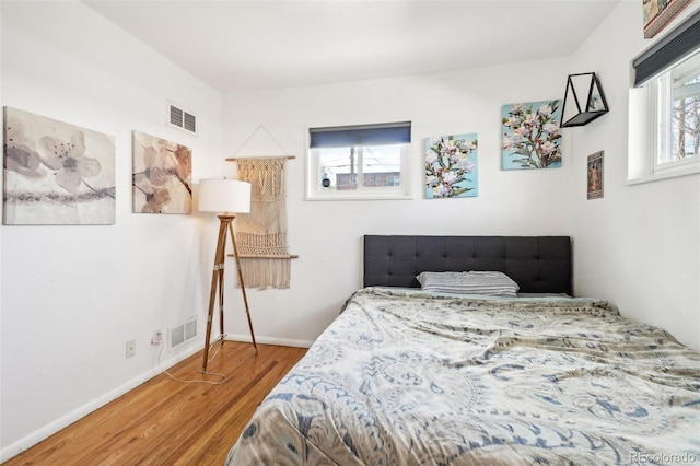 bedroom featuring wood finished floors, baseboards, and visible vents