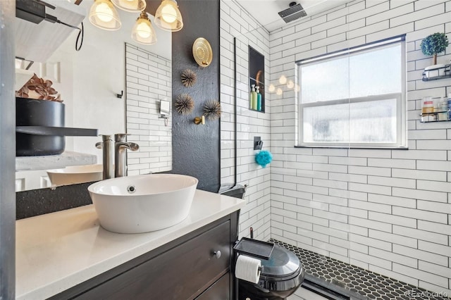 full bathroom with a tile shower and vanity