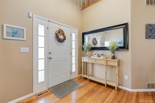 foyer entrance with light wood-style flooring, visible vents, and baseboards