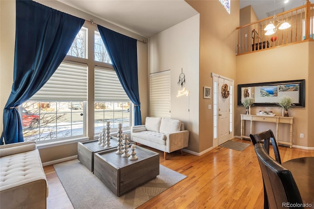 living room featuring a towering ceiling, baseboards, and wood finished floors