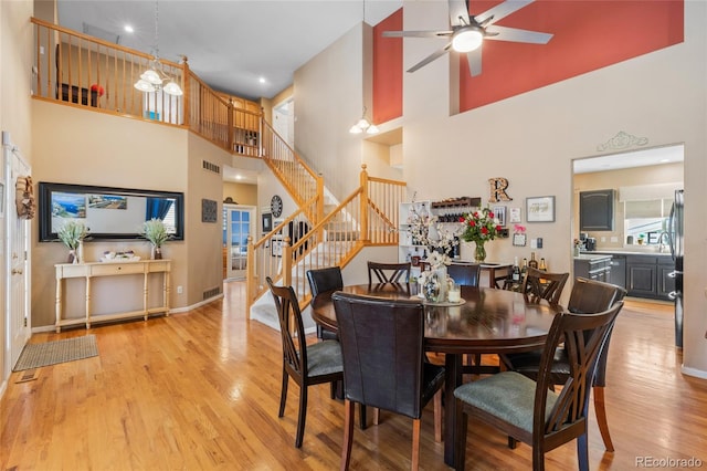 dining area with light wood-style floors, baseboards, stairs, and visible vents