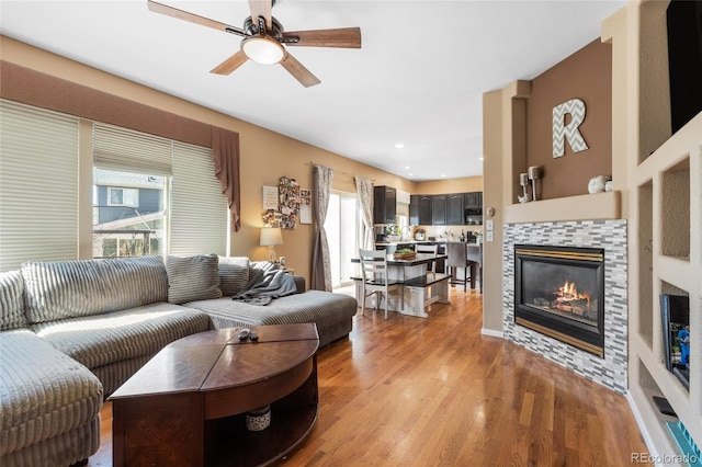 living room featuring light wood-style floors, a fireplace, and a ceiling fan