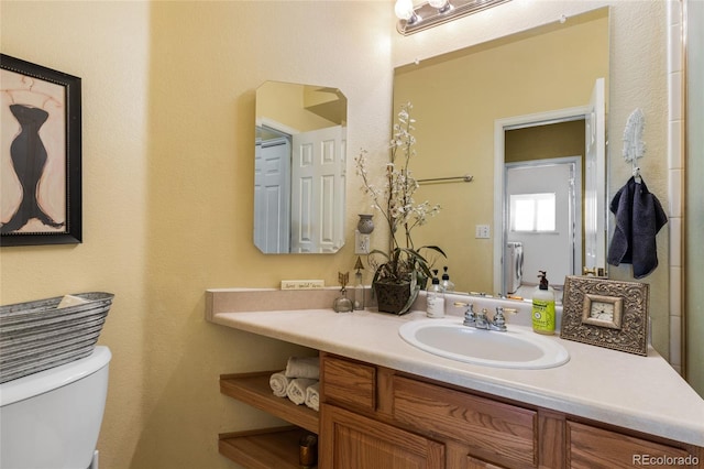 bathroom featuring toilet, washer / dryer, and vanity