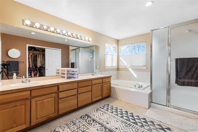 bathroom featuring a bath, a stall shower, a spacious closet, and a sink