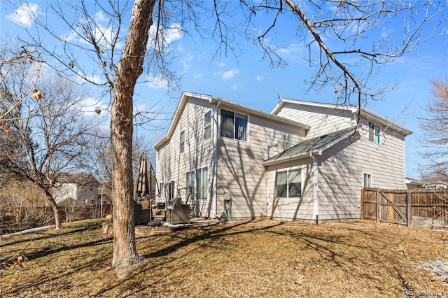 rear view of house featuring a lawn and fence