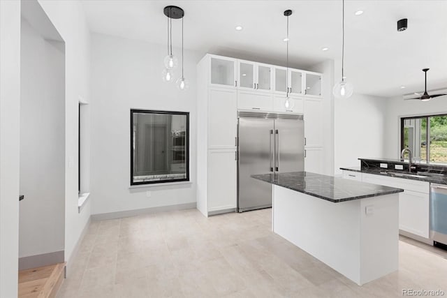 7916 Cozart Ln, Salida, CO 81201 - kitchen with stainless steel appliances, dark stone counters, a kitchen island, glass insert cabinets, and white cabinetry